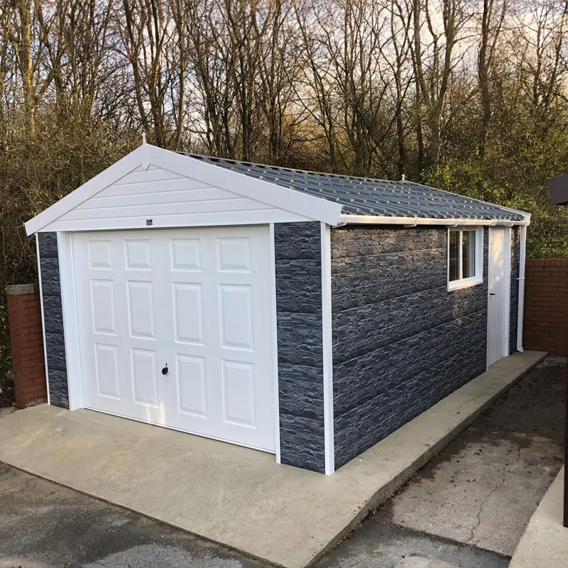 Detached garage with a white panel door, dark stone walls, and a gray metal roof; side door and a window on the right.