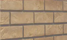 Close-up of a beige brick wall with dark gray mortar lines.
