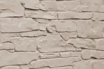 Beige stacked stone wall with irregular rectangular stones and visible mortar lines