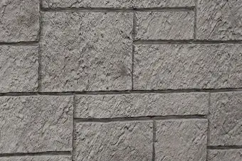 Gray stone wall with rectangular blocks and rough, textured surface.